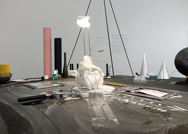 Nikolaus Gansterer, Transpositionsmodell II (Thinking<>Feeling<>Drawing<>Knowing), 2015, table, drawings, objects, video loop; installation view at the exhibition: Drawing Now, Albertina Museum, Vienna, Austria.